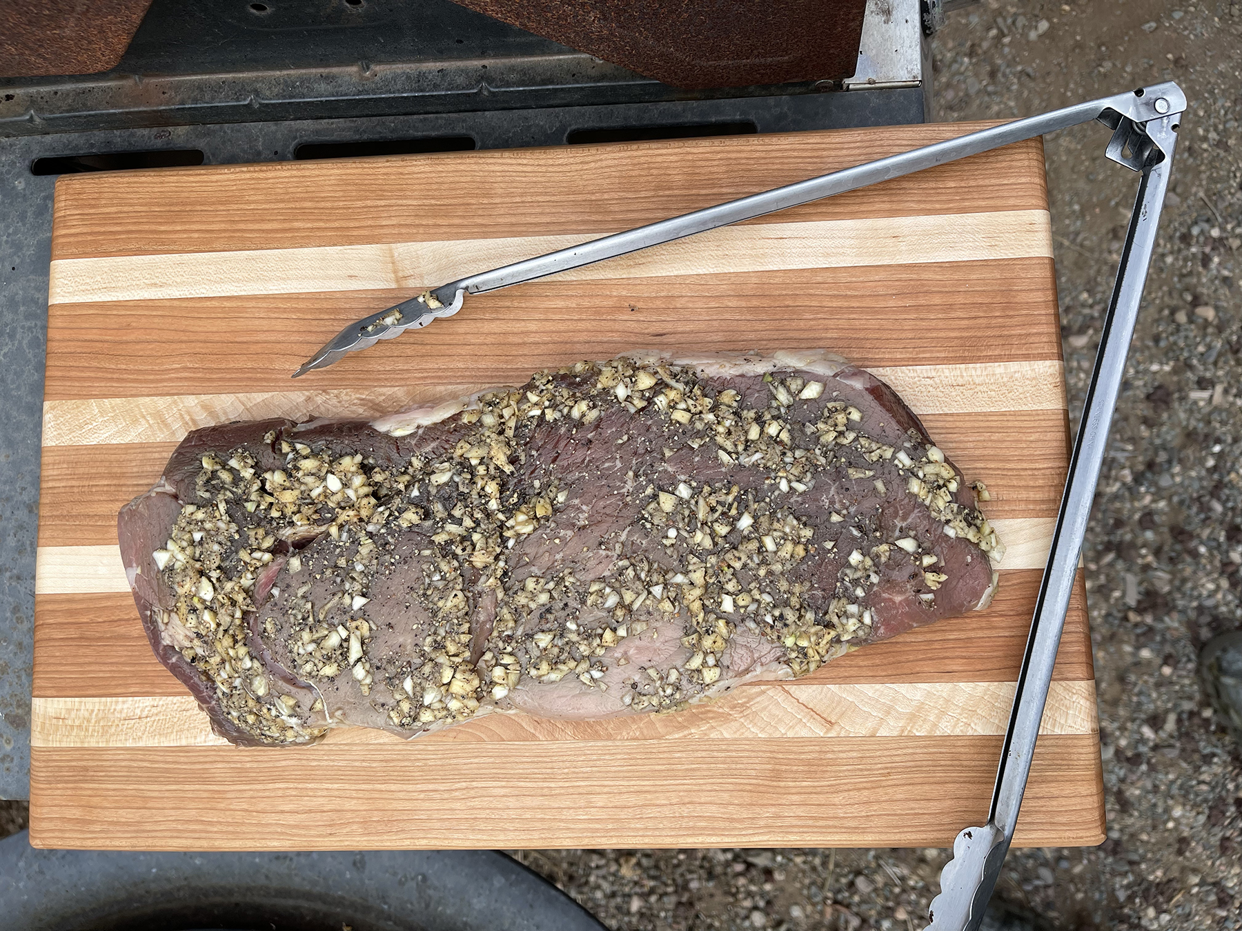 Garlic, salt & pepper on London Broil ready for the grill. On our Cherry Cutting Board with Maple accents.